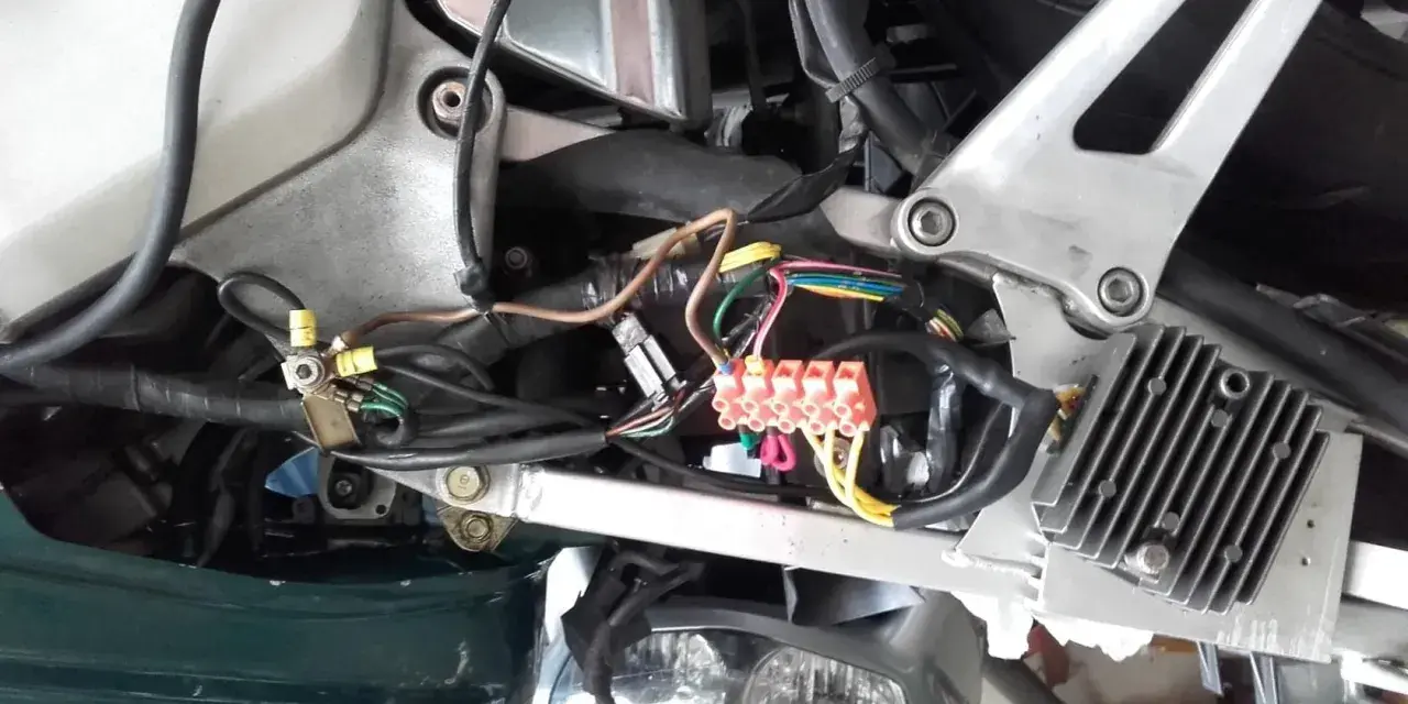 Widok instalacji elektrycznej skutera z widocznymi bezpiecznikami i przewodami.