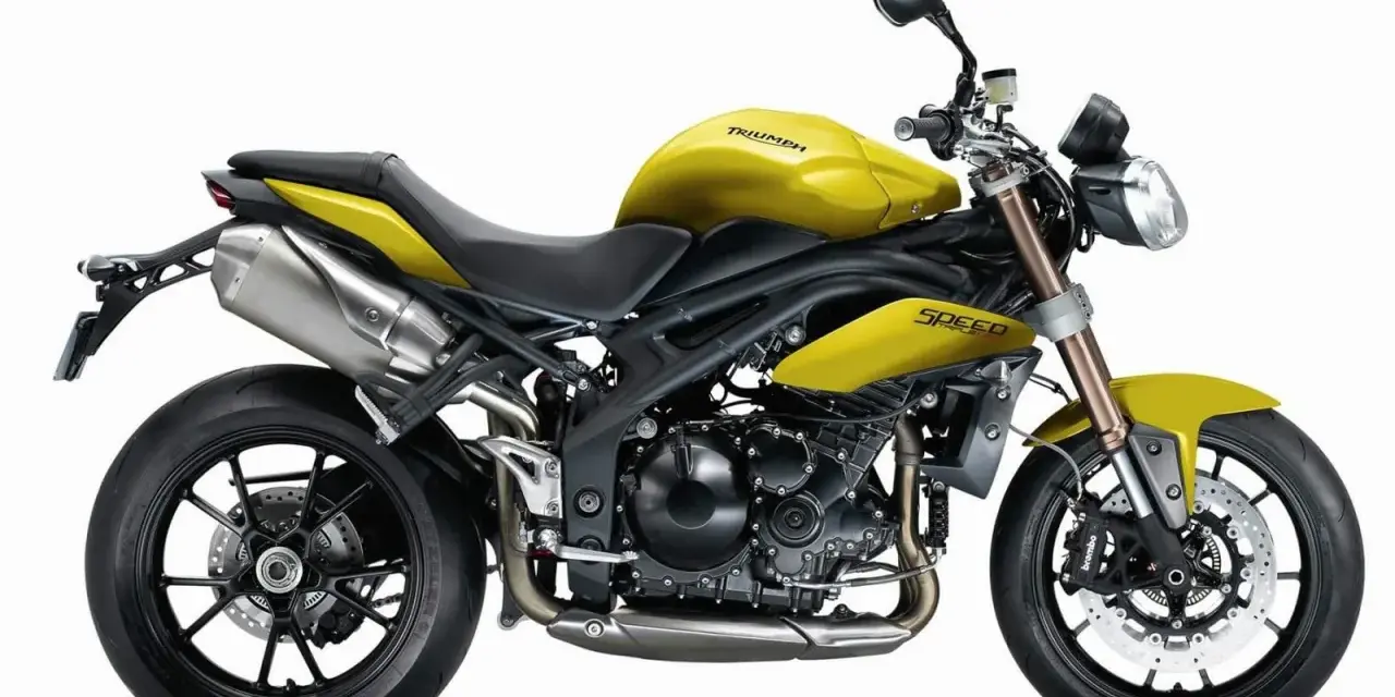 Żółty motocykl Triumph Speed Triple 1050 z czarnymi felgami i wydechem.