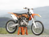 Pomarańczowy KTM SX 125 gotowy do osiągnięcia v-max na górskich trasach.