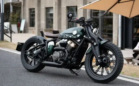 Stylowy, zielony motocykl typu cruiser z brązowym siedzeniem. Idealny do miejskich podróży, mógłby znaleźć się w rankingu motocykli cruiser.