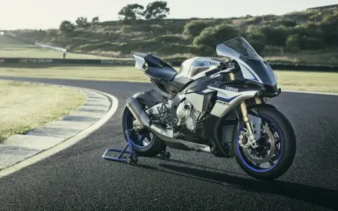 Srebrno-niebieski motocykl Yamaha R1M na torze wyścigowym, gotowy do jazdy.