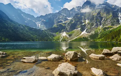 Kamienista droga na Morskie Oko prowadzi przez malownicze Tatry. Jezioro odbija skaliste szczyty i zielone lasy.