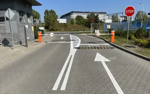 Przed wjazdem na teren hotelu Mercure widać szlabany i znaki ostrzegawcze: STOP, strzałki kierunkowe i progi zwalniające.