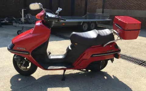 Czerwony skuter Honda Spacy 250 z kufrem, gotowy do podróży.