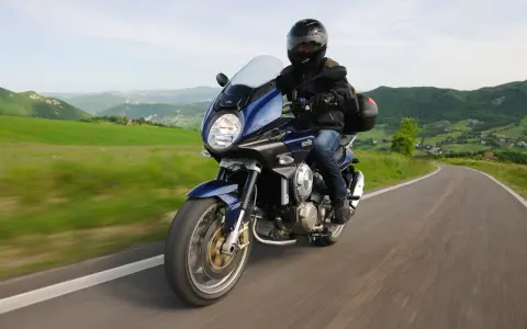 Motocykle szosowo turystyczne przemierzają malownicze, zielone wzgórza.