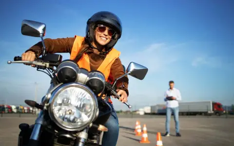 Uśmiechnięta kursantka na motorze, gotowa na egzamin. Zastanawiasz się, jakie prawo jazdy na motor 1000? To kategoria A.