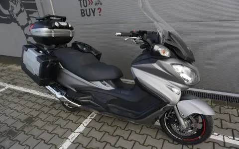 Srebrny Suzuki Burgman 650 Executive z kuframi, gotowy na dalekie podróże.