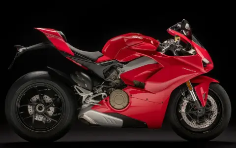 Czerwony motocykl Ducati Panigale V4 na czarnym tle. Poznaj jego imponującą moc i sprawdź, jaka jest jego ducati panigale v4 cena.