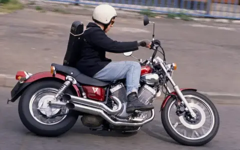 Motocyklista na czerwonym Yamaha Virago 535, z futerałem na instrumenty z tyłu. Dane techniczne tego modelu są imponujące.