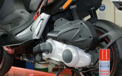 Skuter Gilera z widocznym silnikiem 4t. Może to być przyczyna, dla której po dodaniu gazu silnik się dusi. Obok stoi spray do czyszczenia hamulców.