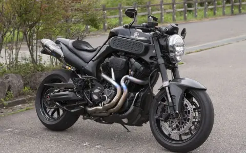 Czarny Yamaha MT-01 z customowym wydechem i sportowymi dodatkami, gotowy na jazdę po krętych drogach.