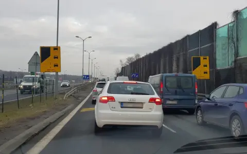 Korek na drodze, znaki informują o zalecanej zasadzie ruchu "na suwak". Unikaj mandatu, stosuj się do przepisów.