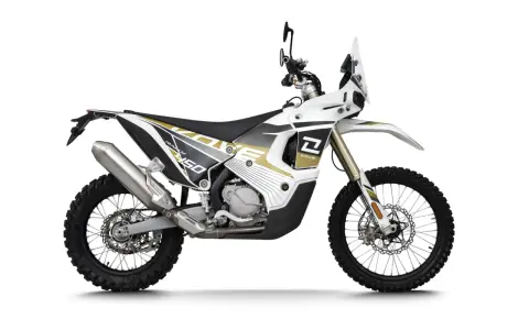 Biały motocykl Kove 450 Rally z czarnymi i złotymi akcentami, gotowy na przygodę.