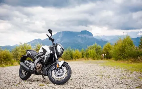 Biało-czarny Bajaj Dominar 400 na tle gór i chmur. Gotowy na przygodę w dziczy.