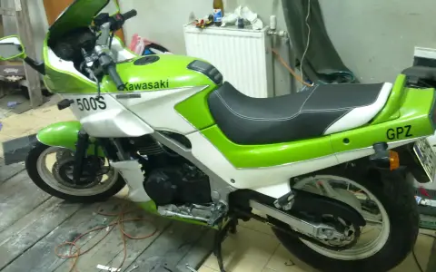 Zielono-biały motocykl Kawasaki GPZ 500 z napisem "GPZ" na tyle. Stoi na drewnianej podłodze w garażu.