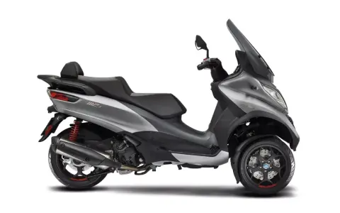 Srebrny Piaggio MP3 500, trójkołowy skuter z czarnym siedzeniem i dużą szybą. Poznaj jego piaggio mp3 500 dane techniczne.