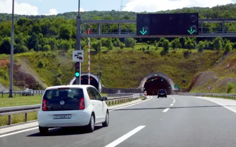 W Chorwacji są płatne autostrady. Biały samochód zbliża się do tunelu, sygnalizacja świetlna zielona.
