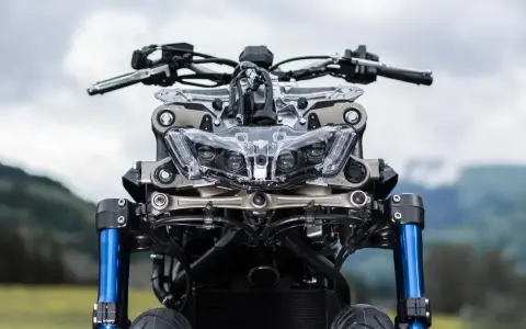 Przód motocykla Yamaha Niken GT z niebieskimi lagami i charakterystycznym, wielopunktowym reflektorem.