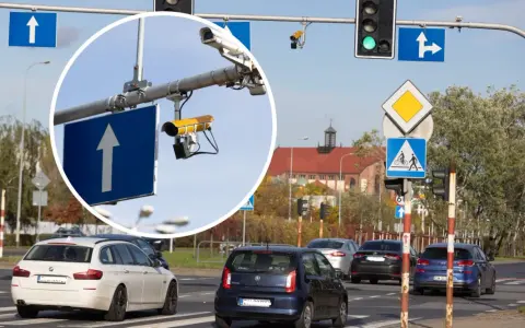 Zbliżenie na kamery monitoringu przy drogowskazie z białym strzałką w górę.