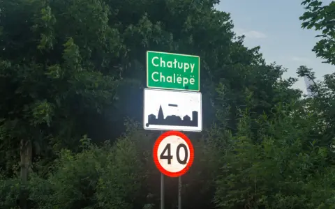 Znak d42: Chatupe Chalëpe, zarys zabudowań i ograniczenie prędkości do 40 km/h.
