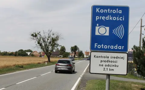 Znak "Kontrola prędkości Fotoradar" informuje, że czy fotoradar musi być oznakowany. Obok droga i pola.