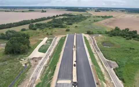 Budowa drogi ekspresowej S2 Siedlce-Biała Podlaska. Nowa nawierzchnia asfaltowa w otoczeniu zieleni i pól.
