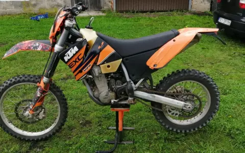Pomarańczowy motocykl KTM 400 EXC na stojaku, gotowy do jazdy po bezdrożach.