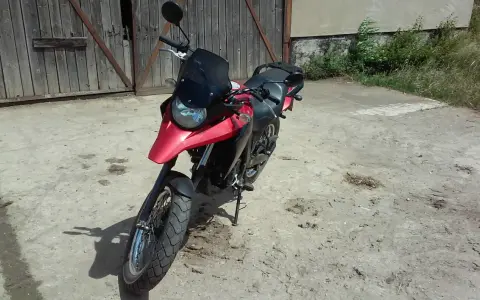 Czerwony motocykl Derbi Terra 125 stoi przed drewnianą stodołą.