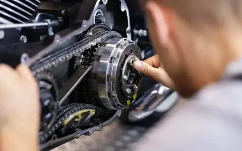 Mechanik reguluje sprzęgło, kluczowy element do nauki, jak zmieniać biegi w motocyklu 125.