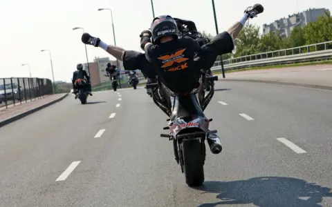Motocyklista wykonuje jazdę na jednym kole, rozkrokiem. Ryzykowne wyczyny mogą skończyć się mandatem.