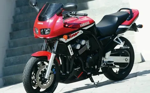 Czerwony motocykl Yamaha Fazer z czarnym siedzeniem i detalami, gotowy do jazdy.