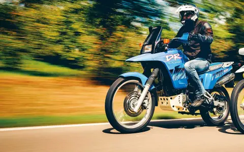 Motocyklista na niebieskim Suzuki DR 800 Big pędzi po drodze. Poznaj suzuki dr 800 big dane techniczne i poczuj wolność.