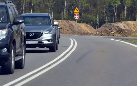 Kierowca próbuje wyprzedzanie na podwójnej ciągłej, ignorując znak ograniczenia prędkości do 70 km/h i ostrzeżenie o dzikich zwierzętach.