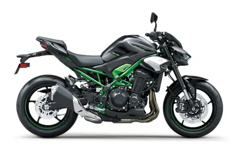 Czarny motocykl Kawasaki Z900 z zielonym stelażem i akcentami. Potężna maszyna gotowa na przygodę.