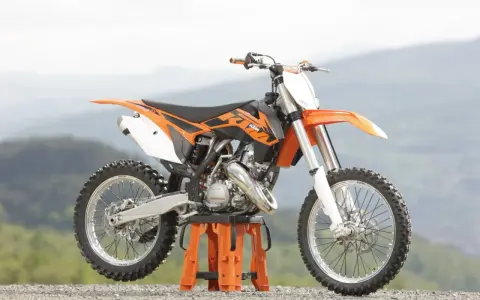 Pomarańczowy KTM SX 125 gotowy do osiągnięcia v-max na górskich trasach.