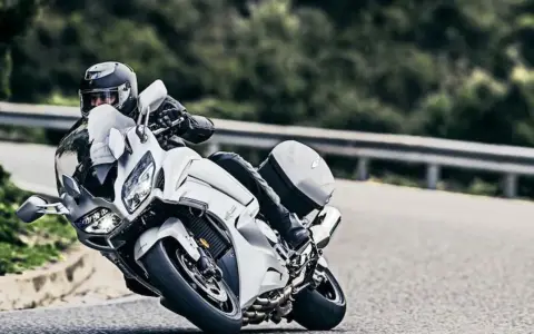 Motocyklista w kasku pochyla się na białym motocyklu Yamaha FJR 1300, pokonując zakręt. Dane techniczne tego modelu są imponujące.