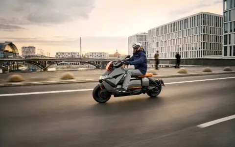 Mężczyzna w kasku jedzie na skuterze BMW CE 04 po mieście.