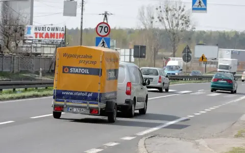 Samochód z przyczepą Statoil jedzie drogą. Znak ograniczenia prędkości 70 km/h sugeruje, ile można jechać na autostradzie w tym miejscu.