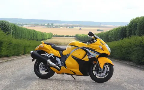 Żółty Suzuki Hayabusa na tle pól i zielonych żywopłotów. Sprawdź aktualną suzuki hayabusa cena!
