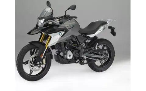 Szary motocykl BMW 310 GS z czarnym siedzeniem i złotymi amortyzatorami, gotowy na przygodę.