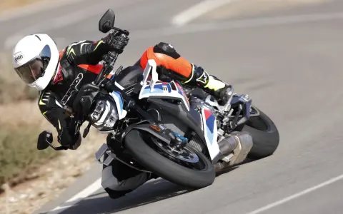 Motocyklista w kombinezonie i kasku pochyla się na zakręcie na sportowym motocyklu BMW. DTC BMW zapewnia kontrolę.