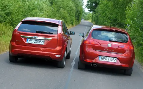 Dwa czerwone auta jadą drogą. Jedno z nich, Ford Focus, próbuje omijanie, podczas gdy Seat Leon wykonuje wymijanie.