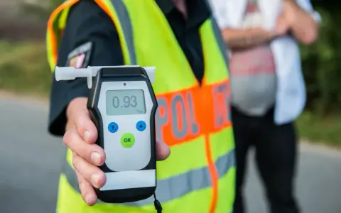 Policjant pokazuje alkomat z wynikiem 0.93 promila. To przekroczenie dopuszczalnej ilości alkoholu w wydychanym powietrzu.