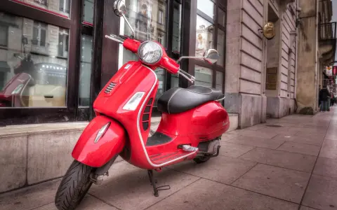 Czerwony skuter Vespa, idealny do miasta. Marzenie o posiadaniu go jest jak marzenie o zdobyciu prawa jazdy na skuter.