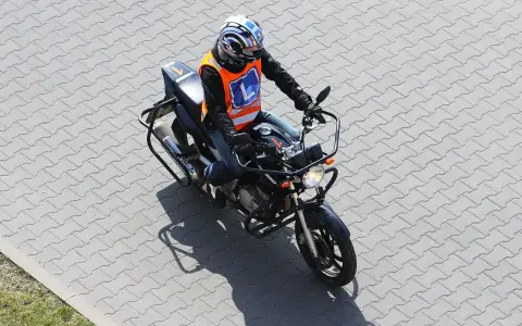 Motocyklista w kamizelce z literą "L" (kategoria A2) na placu manewrowym.