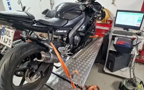 Czarny motocykl na hamowni, przygotowany do testów. Pomiar mocy i momentu obrotowego, czyli blokowanie motocykla na A2, to klucz do optymalizacji osiągów.