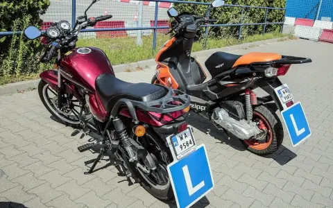 Dwa pojazdy, motorower i skuter, gotowe do nauki jazdy. Na każdym z nich widnieje tablica z literą "L", symbolizująca kartę motorowerową.