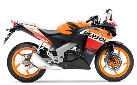 Pomarańczowo-czarny motocykl Honda CBR 125R w barwach Repsol, gotowy do wyścigów.