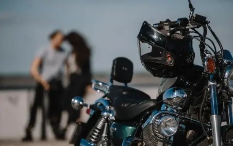 Motocykl z kaskiem na kierownicy, w tle para w czułym uścisku. Idealny dzień na wspólną podróż 4t.