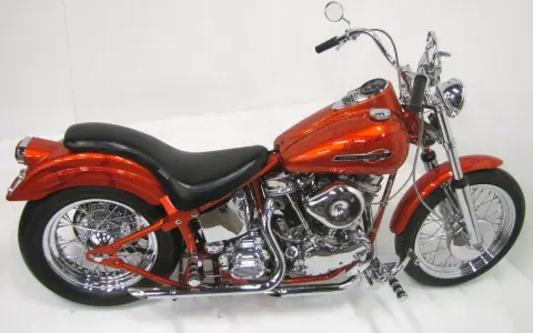 Pomarańczowy motocykl Harley-Davidson z silnikiem panhead, błyszczący chrom i płomienie na baku.